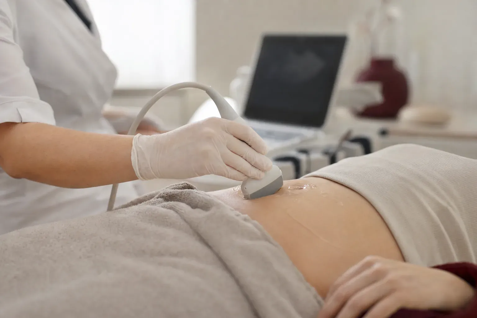 A doctor performs an abdominal ultrasound with the ultrasound machine behind